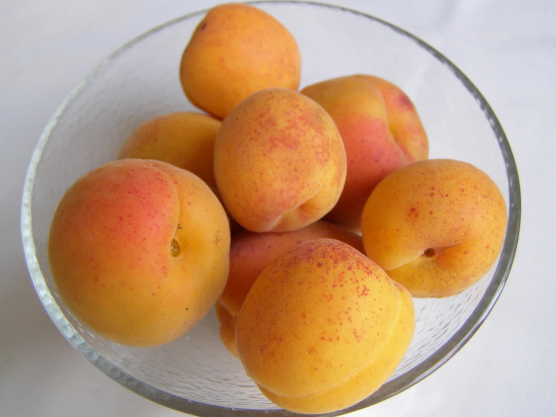Yellow-orange apricots with red blush in a glass bowl