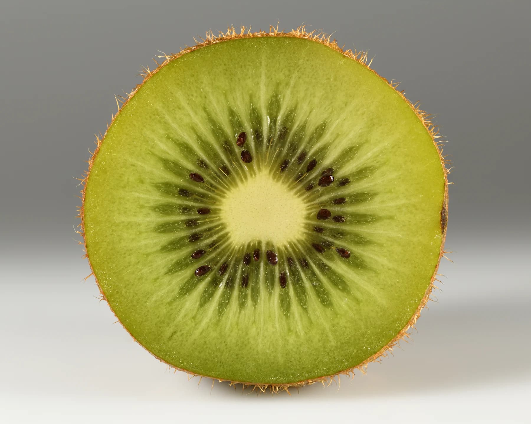Cut green Hayward kiwifruit showing a pale center and small black seeds
