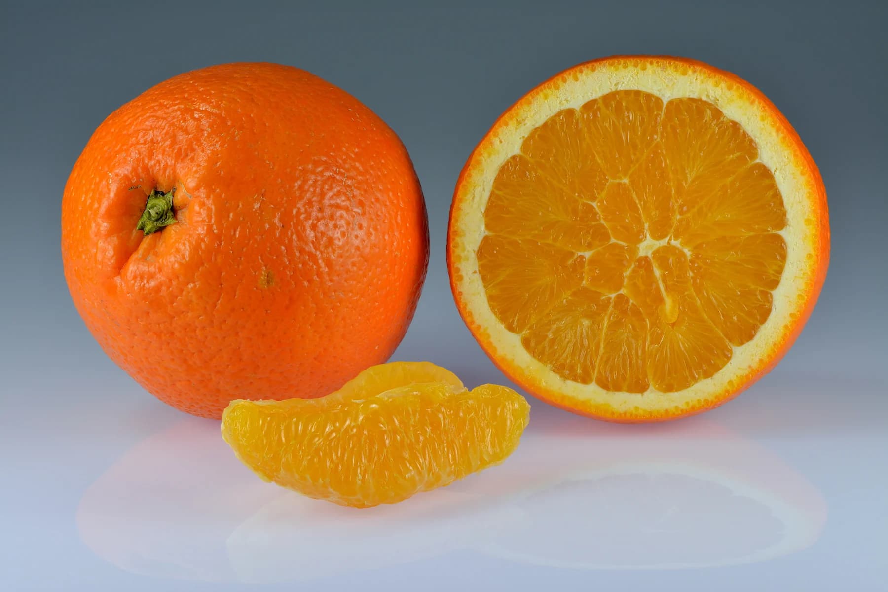 Whole orange, orange half and a peeled segment